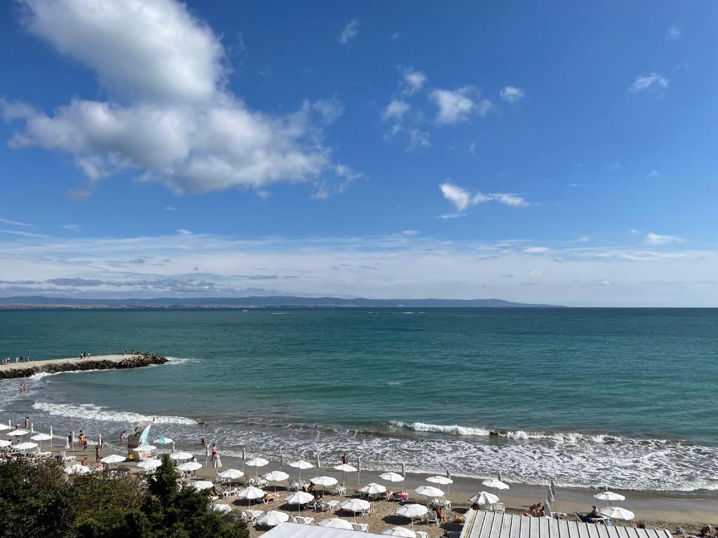 ein Strand mit Sonnenschirmen und Menschen auf dem Wasser in der Unterkunft Apartment Marina in Pomorie