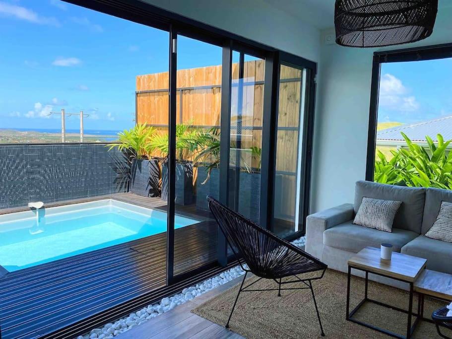sala de estar con piscina y sofá en CASA FERDI 1, logement entier avec piscine privée, en Le Marin