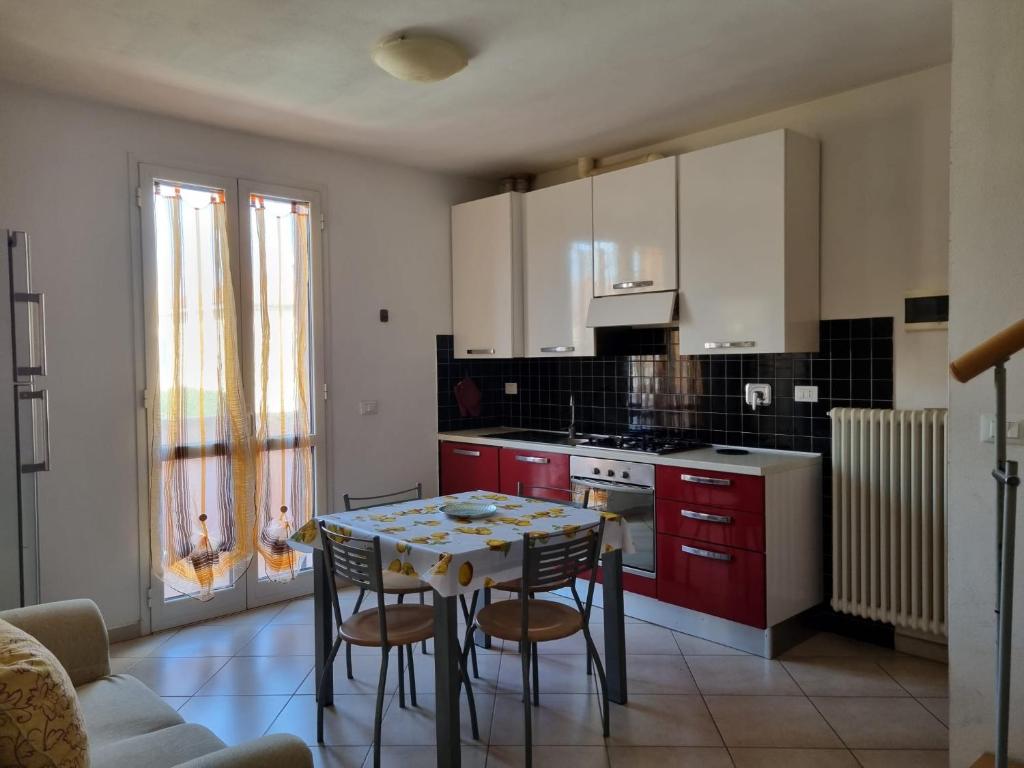 a kitchen with red cabinets and a table and chairs at Giacomo Home in Marina di Cecina
