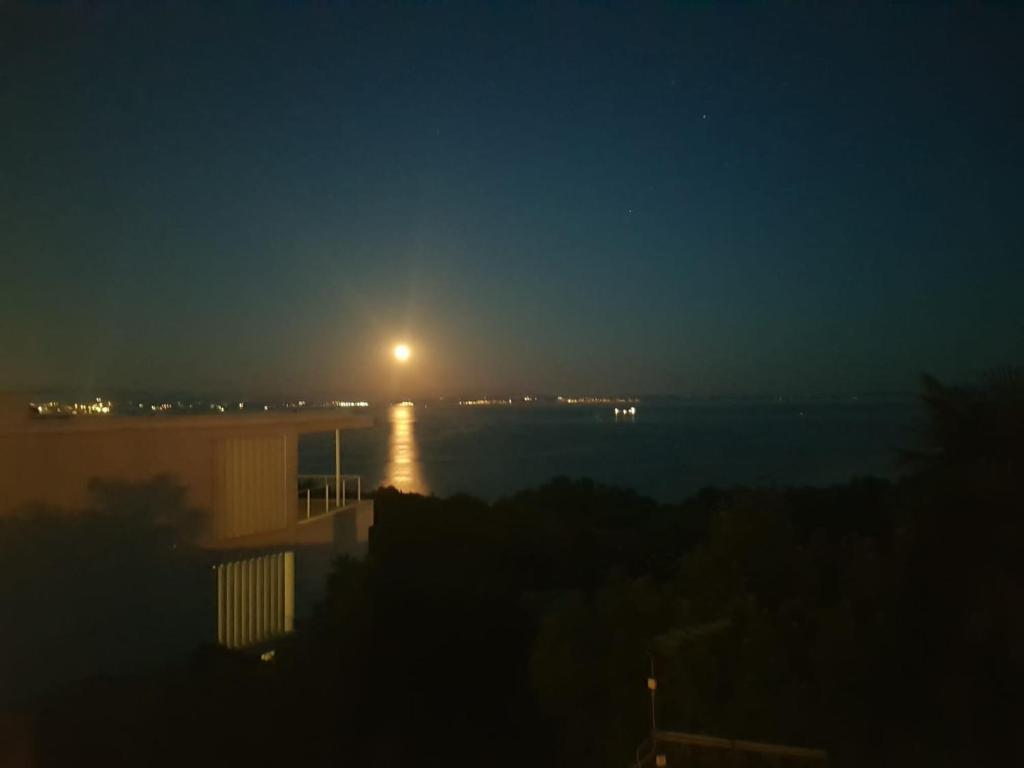 a full moon rising over the water at night at Apartments Baricevic in Opatija