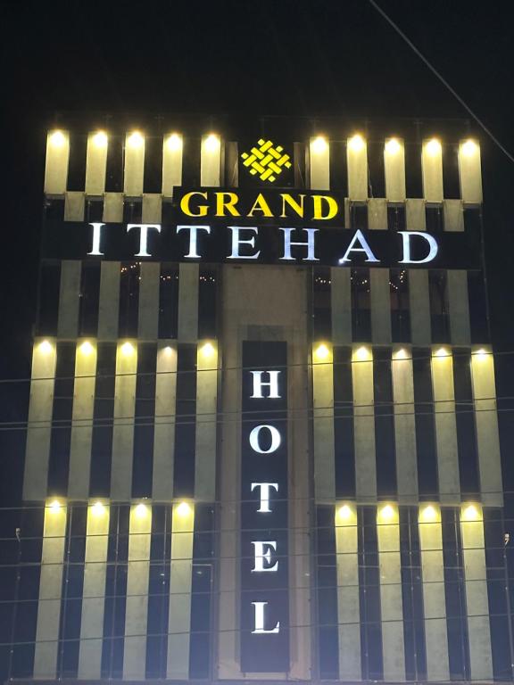a sign for a grand hotel lit up at night at Grand Ittehad Boutique Hotel in Lahore