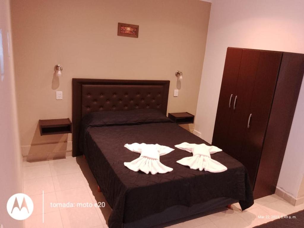 Un dormitorio con una cama con dos vestidos blancos. en DEL SOL APART TERMAL II en Termas de Río Hondo