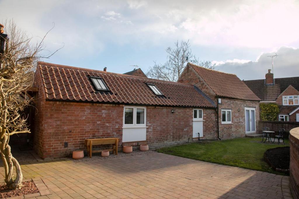 a brick house with a patio and a yard at The Coffin Maker's Cottage, Bunny in West Leake