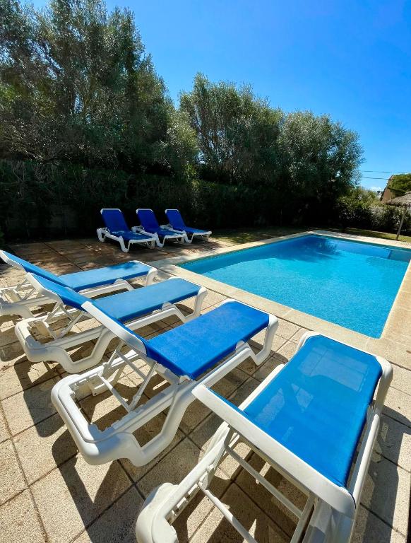 a group of lounge chairs next to a swimming pool at VILLA BLANCA in Cala Ferrera