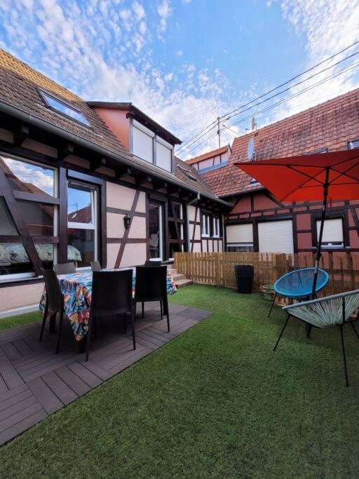 un patio avec une table, des chaises et un parasol dans l'établissement L'Appart avec terrasse - centre historique, à Barr
