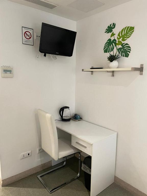 a white desk with a chair and a tv on a wall at L&#39;Oasis Montparnasse in Paris