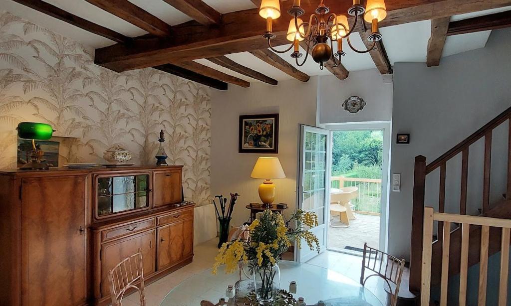 ein Wohnzimmer mit einem Kronleuchter und einem Tisch mit Blumen in der Unterkunft Logis des Fées, spa, piscine et jardin in Baugé
