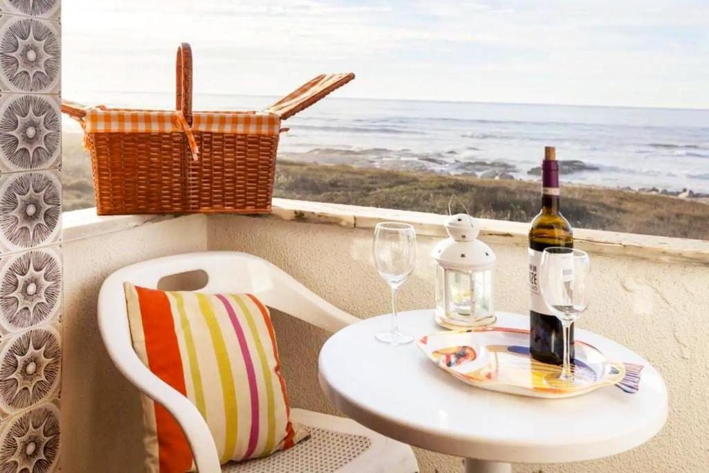un tavolo con una bottiglia di vino e un bicchiere di One bedroom house with sea view enclosed garden and wifi at Moledo a Moledo