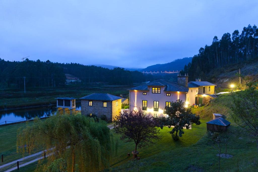 una casa con luces encendidas en un campo por la noche en Finca Goleta, en Foz