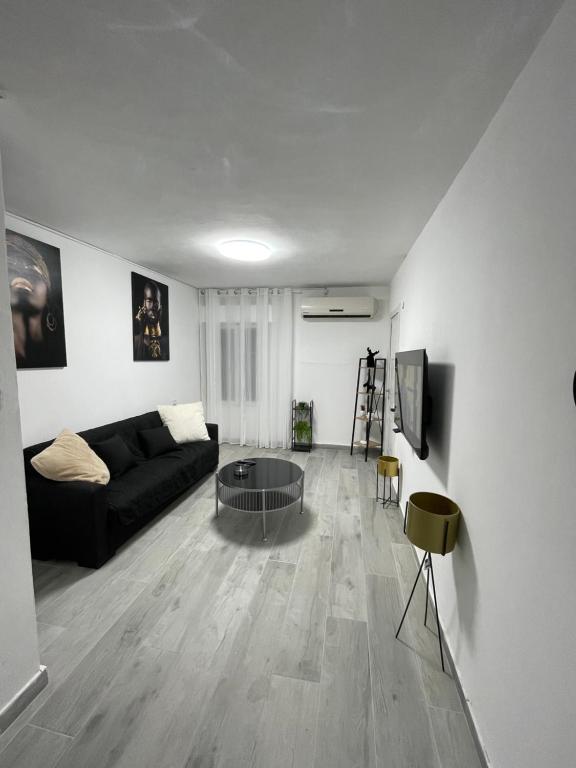 uma sala de estar com um sofá preto e uma televisão em לנפוש בכייף בדגניה em Haifa