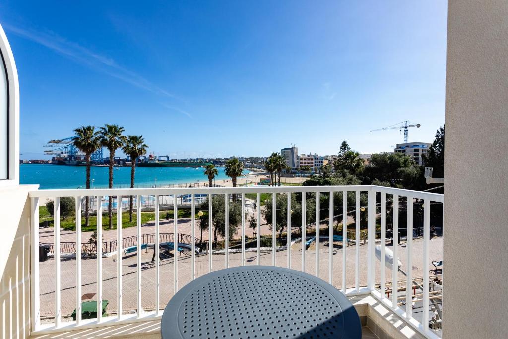 a balcony with a table and a view of the beach at Gospa 58 - 1 bedroom apt in Birżebbuġa