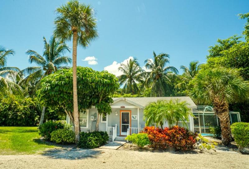 a small house with palm trees in front of it at Baywatch Cottage in Captiva