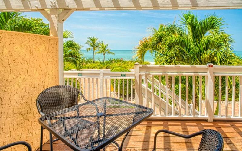a table and chairs on a porch with the ocean at Conch-Captiva Beach Villas in Captiva