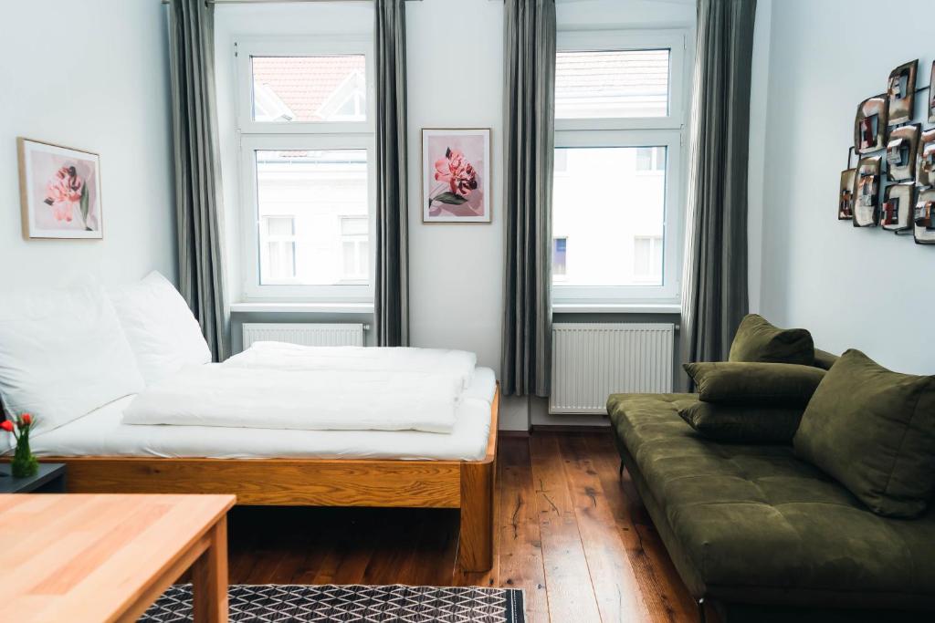 een woonkamer met een bank en 2 ramen bij Wonderful, modern city center apartment in Wenen