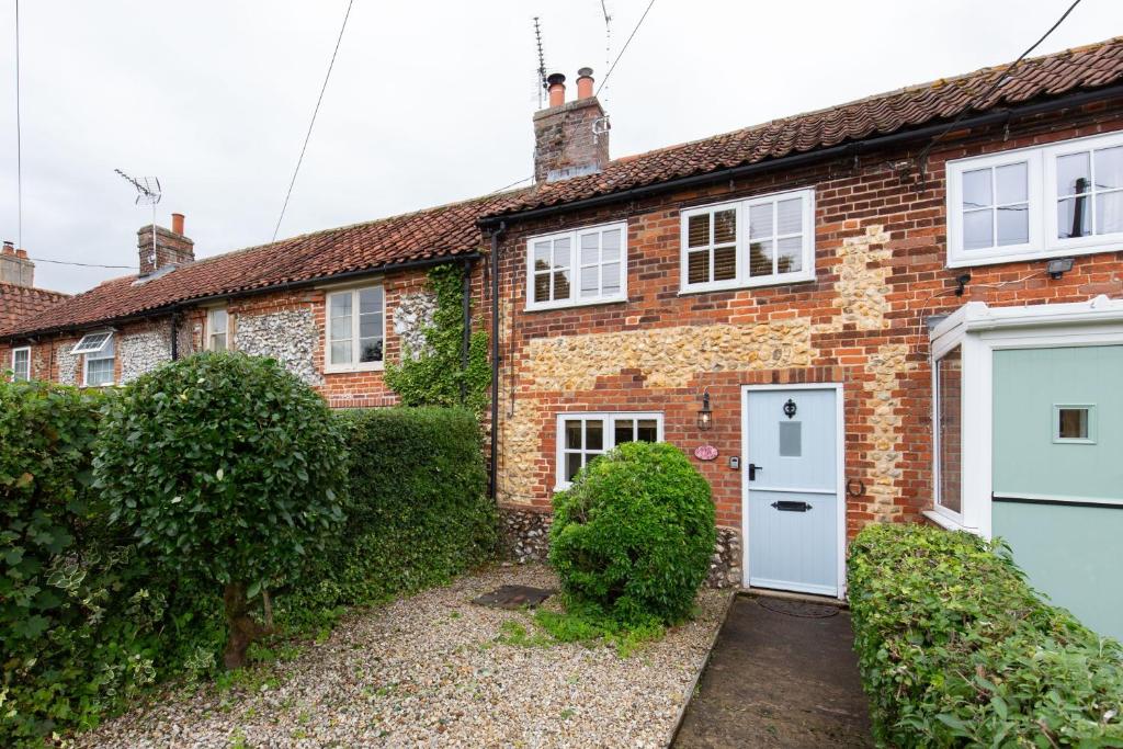 a brick house with a white door at April Cottage in East Rudham