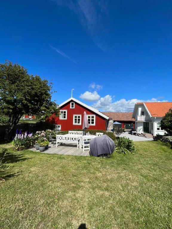 um celeiro vermelho com um banco branco em frente a um quintal em Rovor och Rum Lägenhet Rännet em Skärhamn
