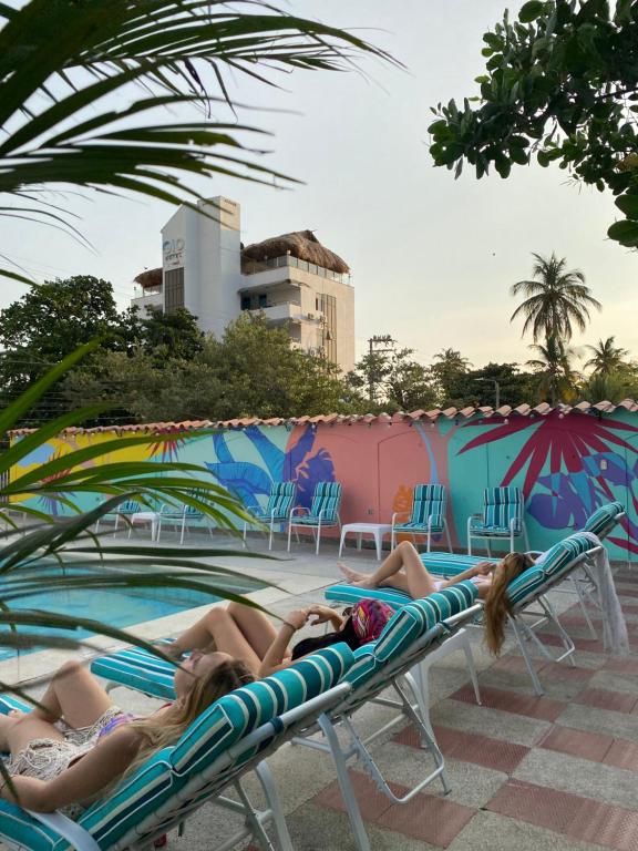 Hotel Los Veleros Santa Marta في سانتا مارتا: وضع سيدتان على كراسي الصالة بمسبح