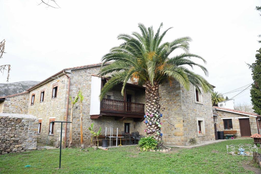 uma palmeira em frente a um edifício de pedra em La casona de Llano em Los Corrales de Buelna