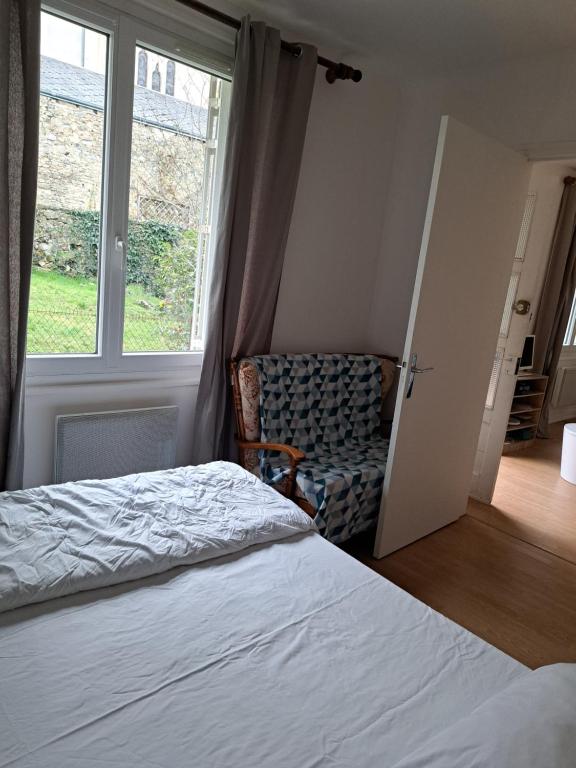 een slaapkamer met een bed, een stoel en een raam bij Vacance solidaire appartement in La Souterraine