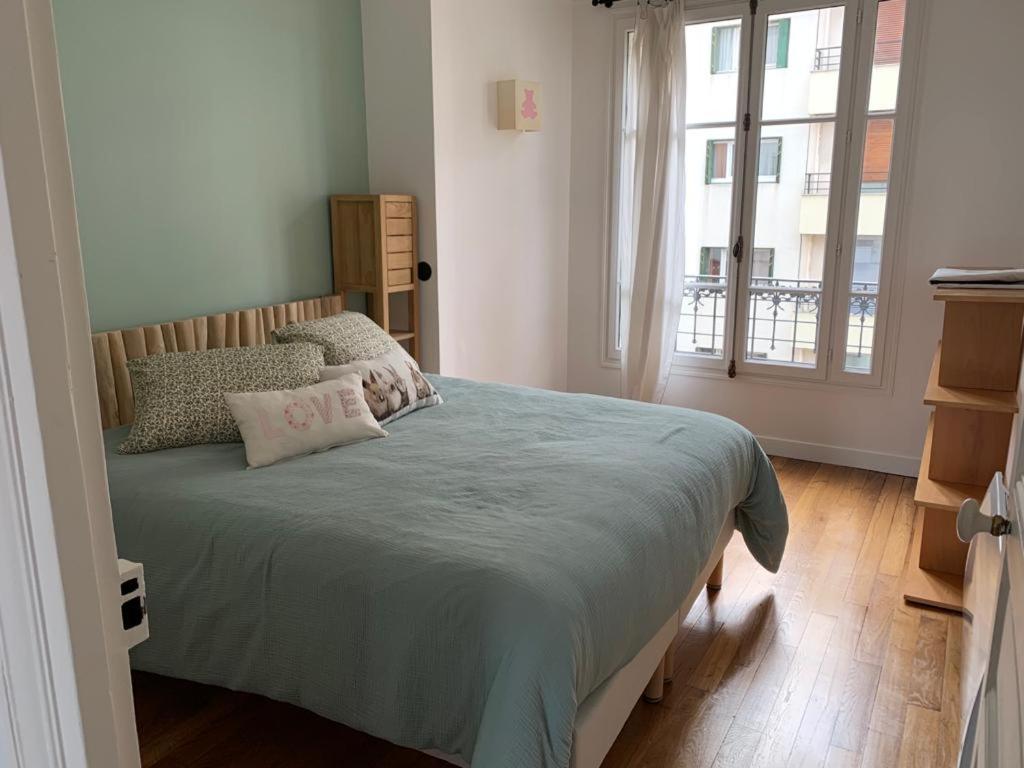 een slaapkamer met een bed met een blauw dekbed bij Joli appartement proche de Paris in Boulogne-Billancourt