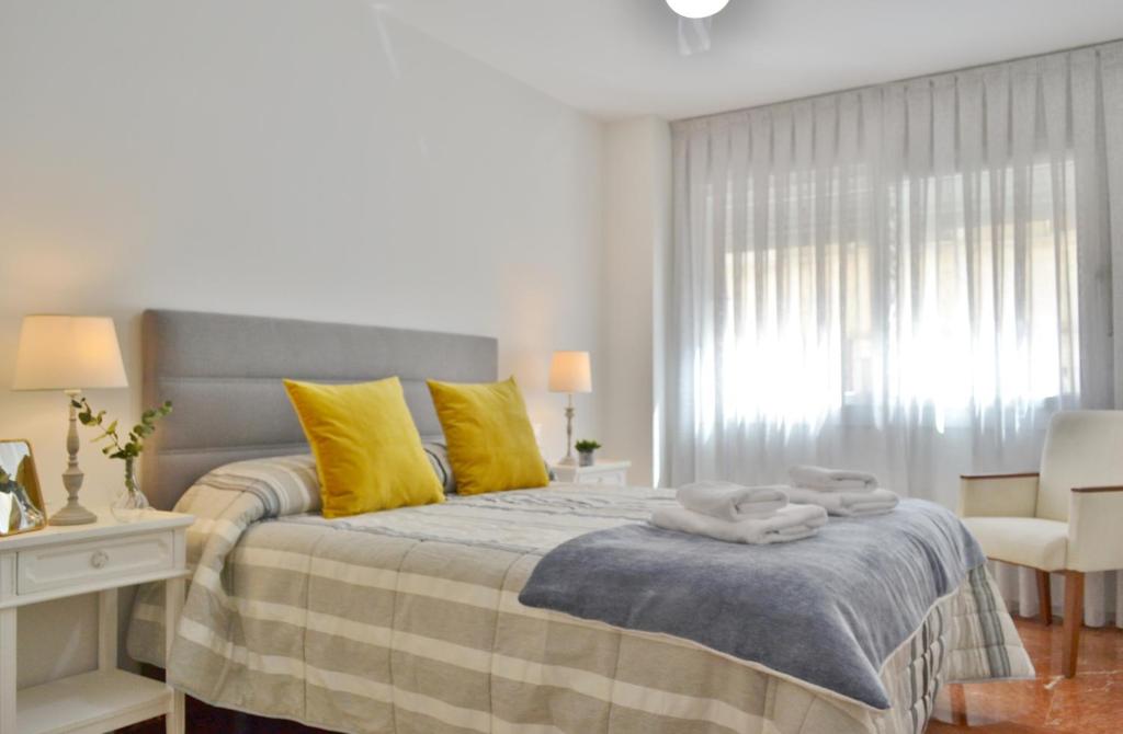Un dormitorio con una cama con almohadas amarillas y una ventana en SunShine Tejares Garden, en Córdoba