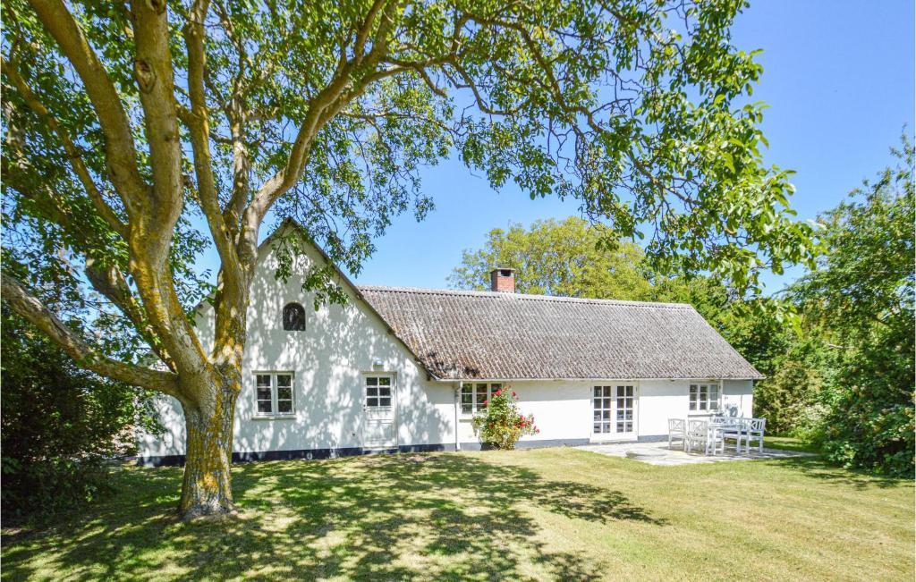 une maison blanche avec un arbre dans la cour dans l'établissement Gorgeous Home In Ask With Kitchen, 