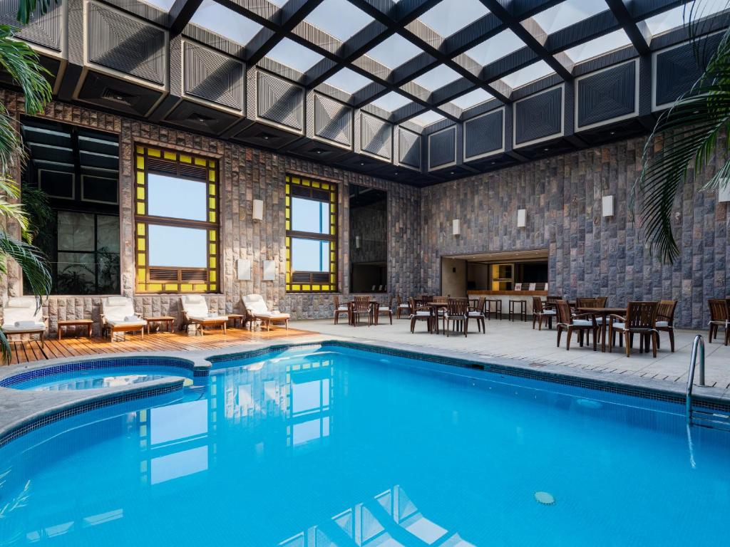 a swimming pool with tables and chairs and a building at Exe Alameda Reforma in Mexico City