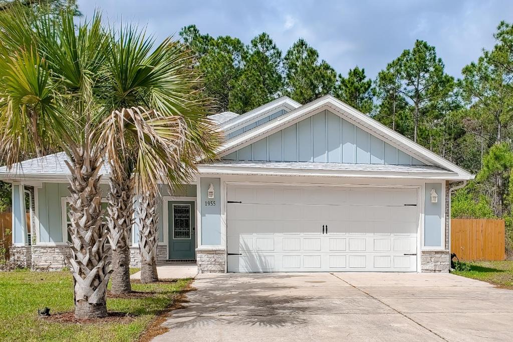 a palm tree in front of a house with a garage at Emerald Coast Cottage in Navarre