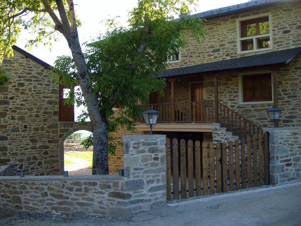 a brick house with a wooden fence in front of it at Alojamiento Rural El atardecer de Sanabria in San Juan de la Cuesta