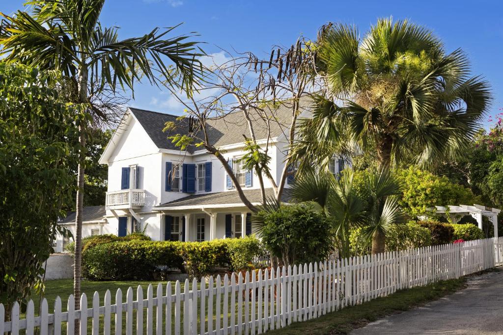 a white picket fence in front of a white house at Tamarind home in Governorʼs Harbour