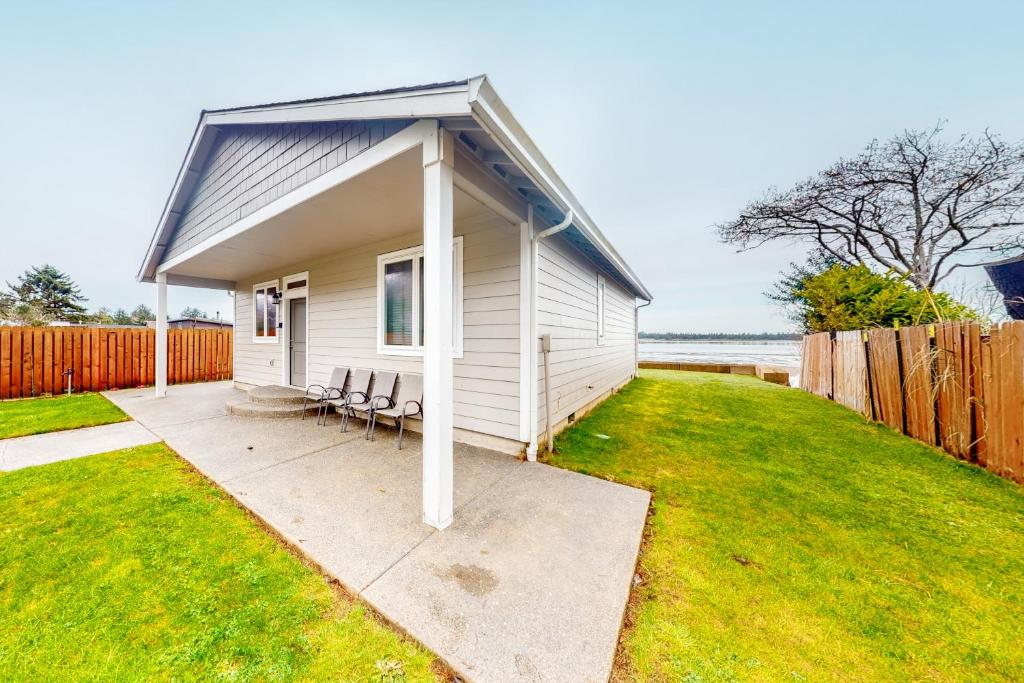 a small white house with chairs in a yard at Sunset Beach House in Coos Bay