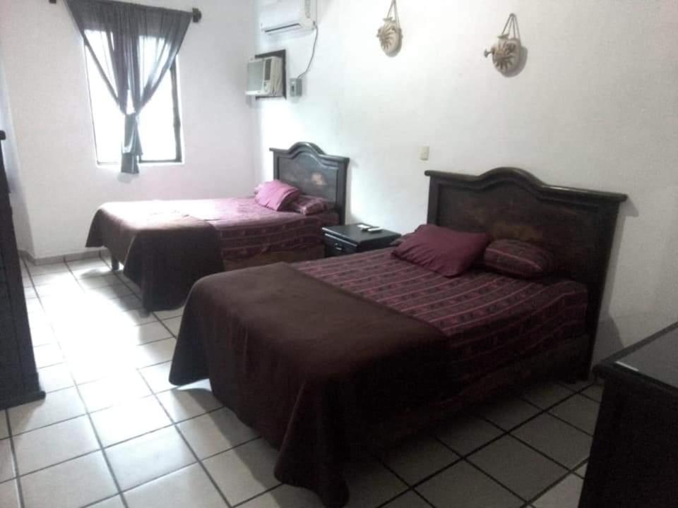 a hotel room with two beds and a window at Hotel Raíz de Sierra in Matlapa
