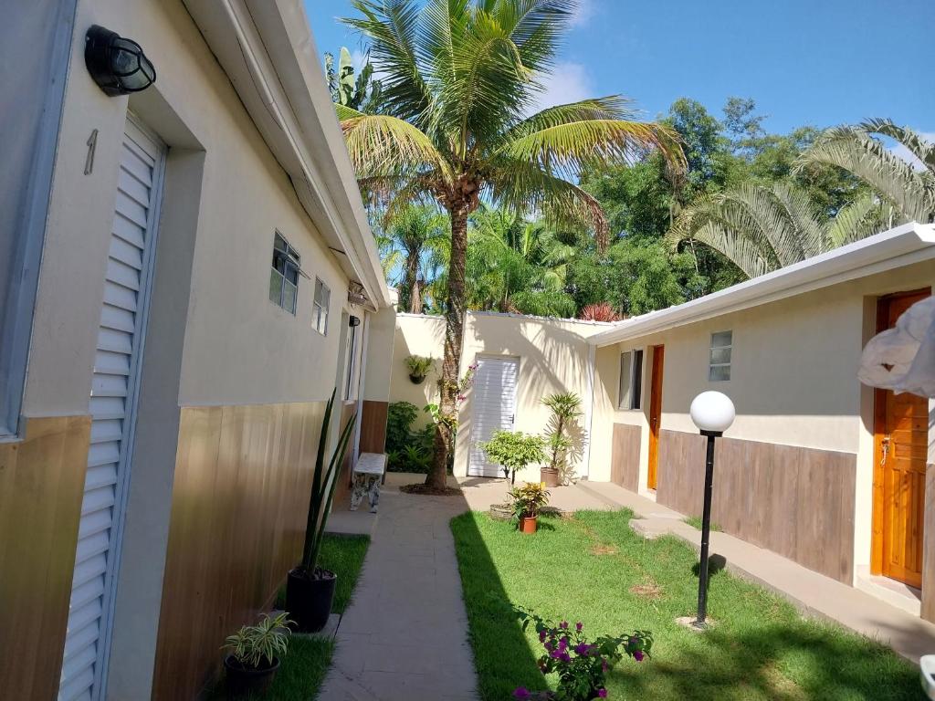 a walkway next to a house with a palm tree at Recanto da Praia Kitnetes in Caraguatatuba