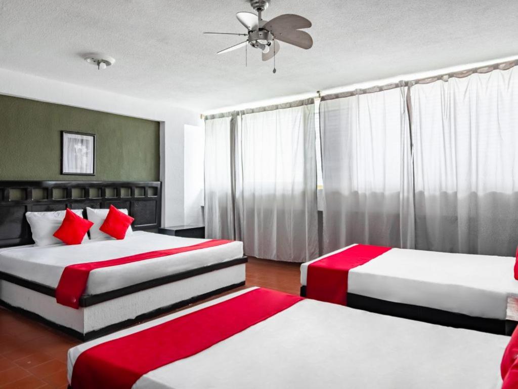 a bedroom with two beds with red and white sheets at Hotel Halley in León