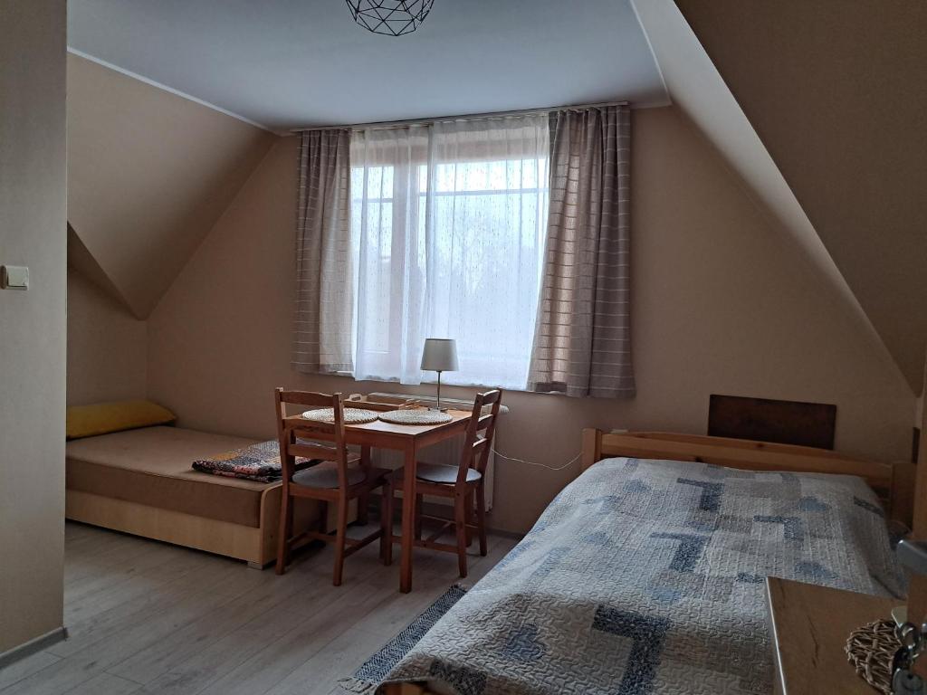 een slaapkamer met een tafel, een bed en een raam bij Mickiewiczówka in Mikoszewo