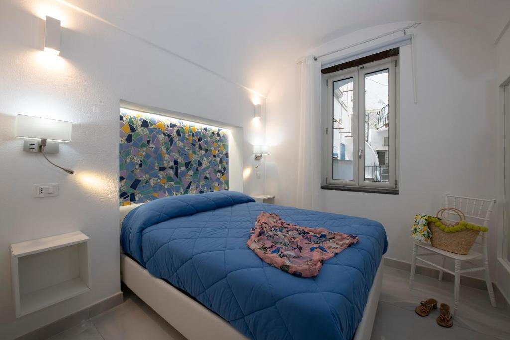 una camera con un letto blu e una finestra di Strit strit centro storico ad Amalfi