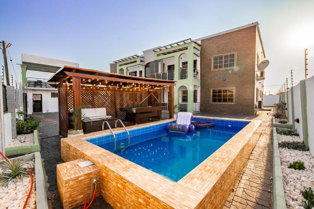 un patio trasero con piscina y una casa en Cloud9 Luxury Apartments en Accra