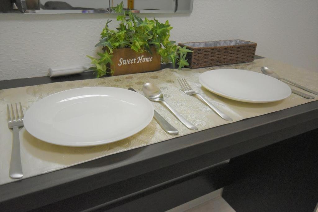 Tresor Misono - Vacation STAY 14287 في سابورو: اثنين من الأطباق البيضاء والأواني جالسين على منضدة