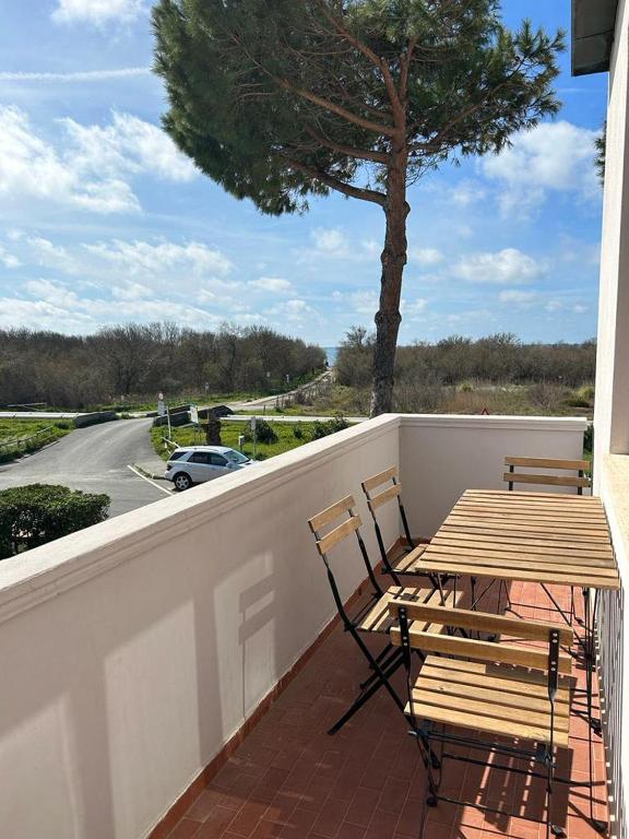 a wooden table and chairs on a balcony with a tree at Appartamento Mare Fuori a Vada by Zoom In Earth in Vada