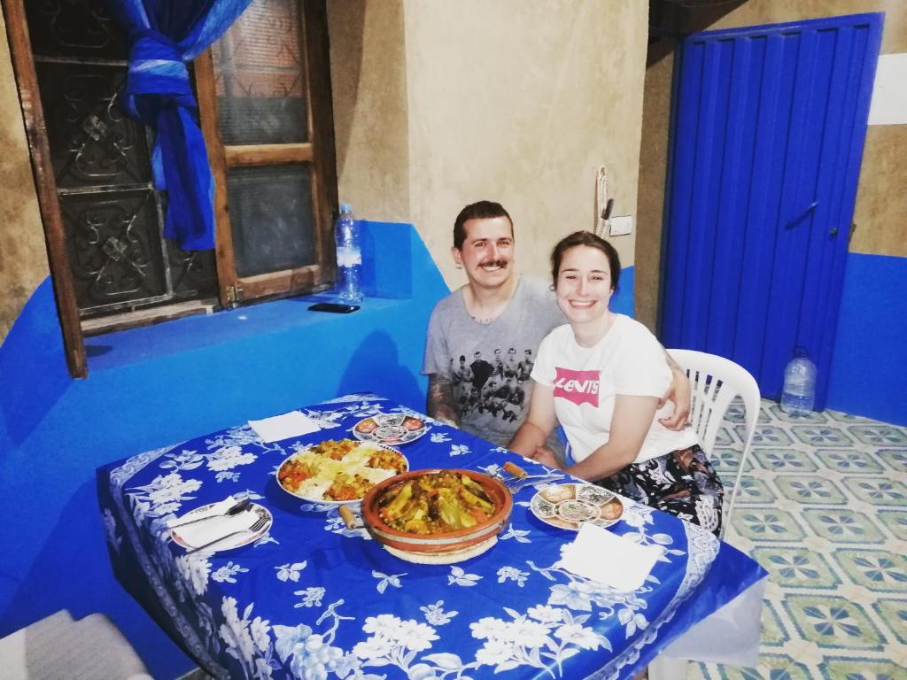 un hombre y una mujer sentados en una mesa con comida en Desert Backpackers hostel, en Merzouga