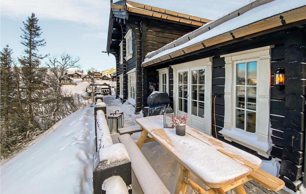 une table en bois sur la terrasse couverte d'une maison dans la neige dans l'établissement Amazing Home In Rauland With Wifi, à Rauland