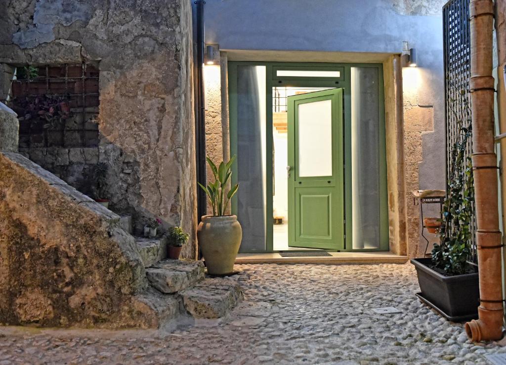a green door in a stone building with a plant at La Corte di Vincenzo in Noto