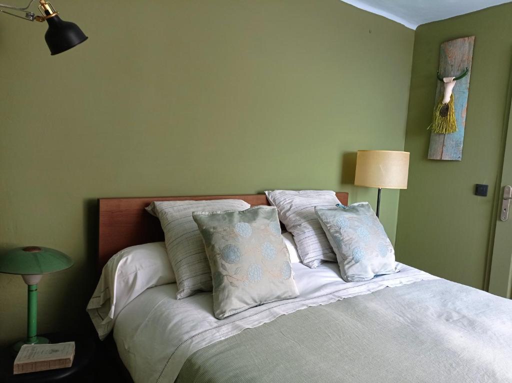 una camera da letto con letto, lenzuola e cuscini bianchi di La Fontaine a Bargème