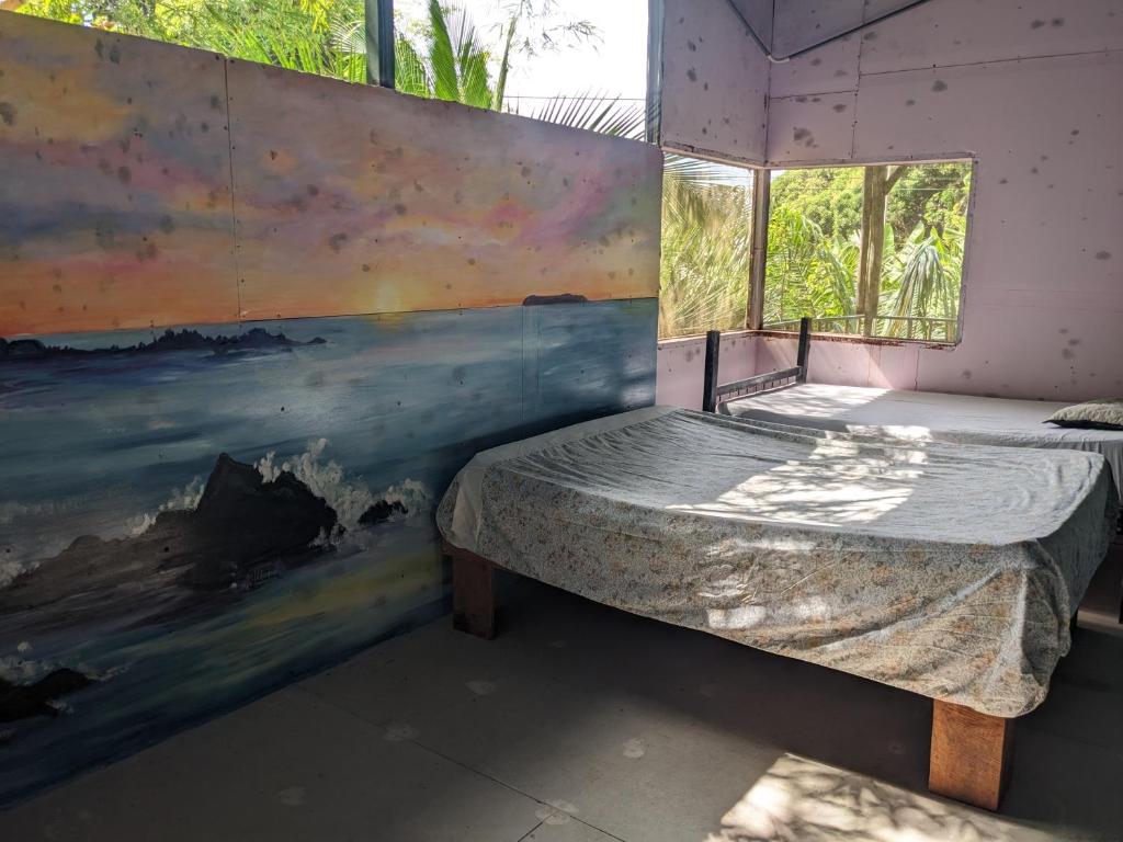 a room with a bed and a painting on the wall at Ecobosque el mar in Rancho Quemado