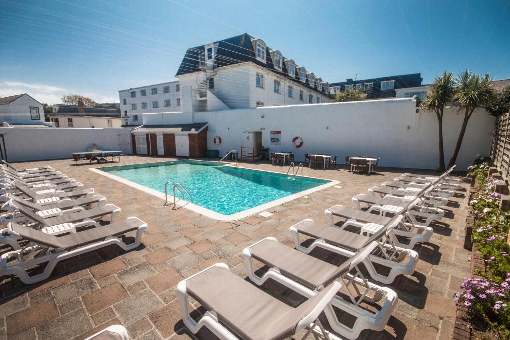 a pool with chaise lounge chairs and a hotel at Norfolk Hotel in Saint Helier Jersey