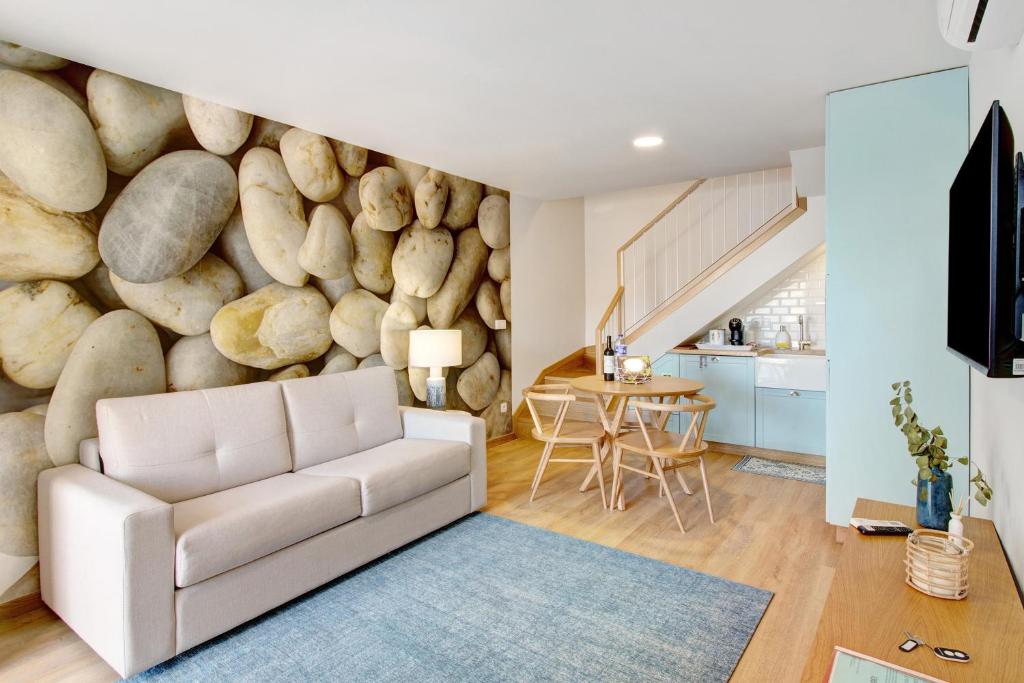 a living room with a white couch in front of a rock wall at Casa do Calhau in Câmara de Lobos