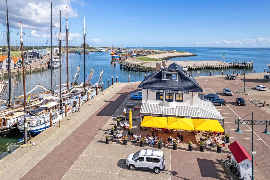 een uitzicht op een jachthaven met een gebouw waar mensen buiten zitten bij Havenhotel At Sea Texel in Oudeschild