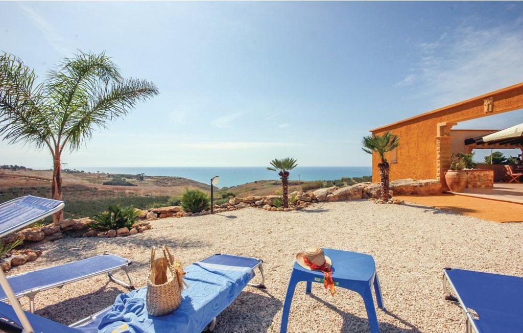 un patio con 2 sillas azules y el océano en Baglio Mediterraneo, en Borgo Bonsignore