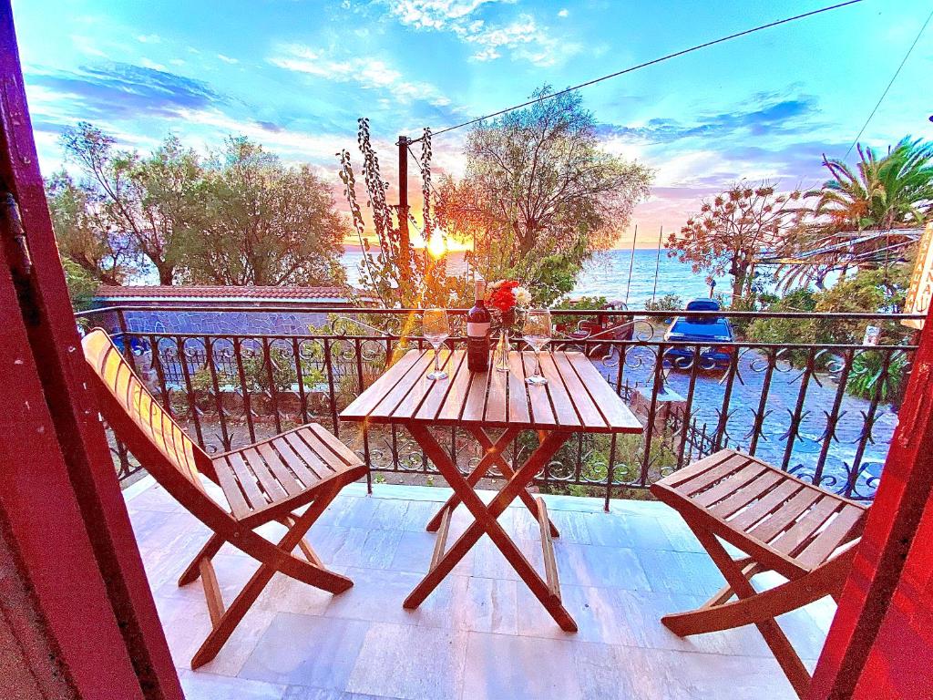 een houten tafel en 2 stoelen op een balkon met uitzicht op de oceaan bij Hermes Hotel in Mithimna