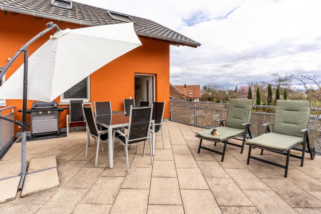 een patio met een tafel en stoelen en een parasol bij Leppert in Schwanau